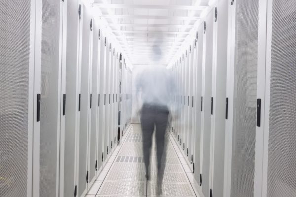 Blurred technician walking to the camera in a large data center